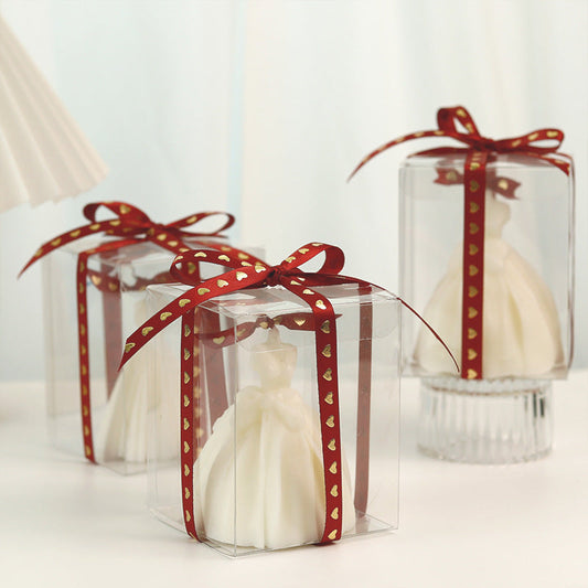 White dress-shaped decorative candle in clear box with red ribbon